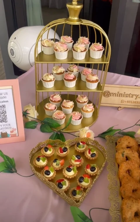Cupcakes and fruit tartlets arranged on gold dessert stands